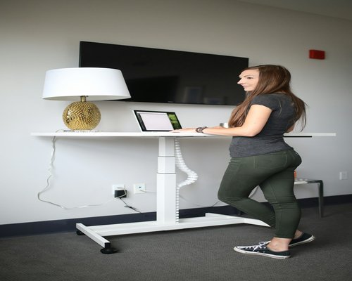 Person adjusting monitor height on a desk